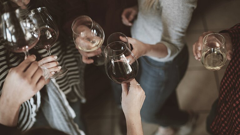 Hotelgäste stoßen mit Weingläsern bei einem Fest im Hotel Goldener Berg an